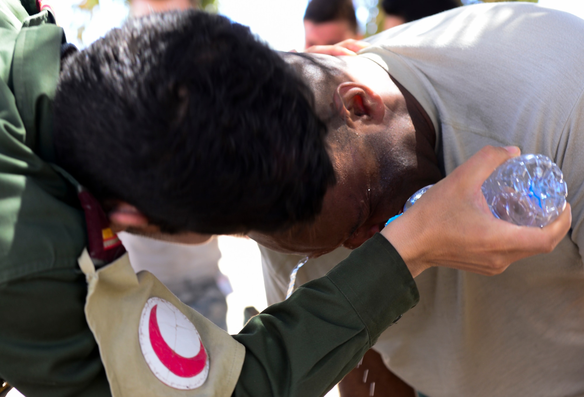 A Royal Moroccan Armed Forces medic pours water on U.S. Air Force Tech. Sgt. Kevin Foster, 403rd Security Forces Squadron security force member, after he received a level one exposure to Oleoresin Capsicum pepper spray as part of a non-lethal weapons course during AFRICAN LION 16 at Tifnit, Kingdom of Morocco, April 23, 2016. Foster is one of twenty Air Force Reservists and Guardsmen participating in the annual exercise. (U.S. Air Force photo by Senior Airman Krystal Ardrey/Released)