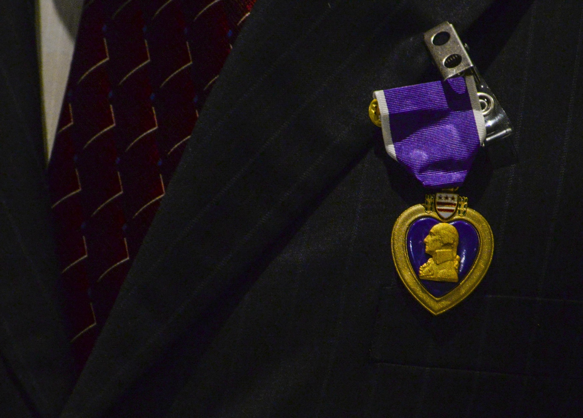 The Purple Heart hangs on retired Airman 1st Class Julius Farrar’s jacket during his ceremony at Nellis Air Force Base, Nev., April 28, 2016. Being in the mountains of Korea tested Farrar and the men he was stationed with, but even with all the obstacles the Airmen endured. (U.S. Air Force photo by Airman 1st Class Kevin Tanenbaum)