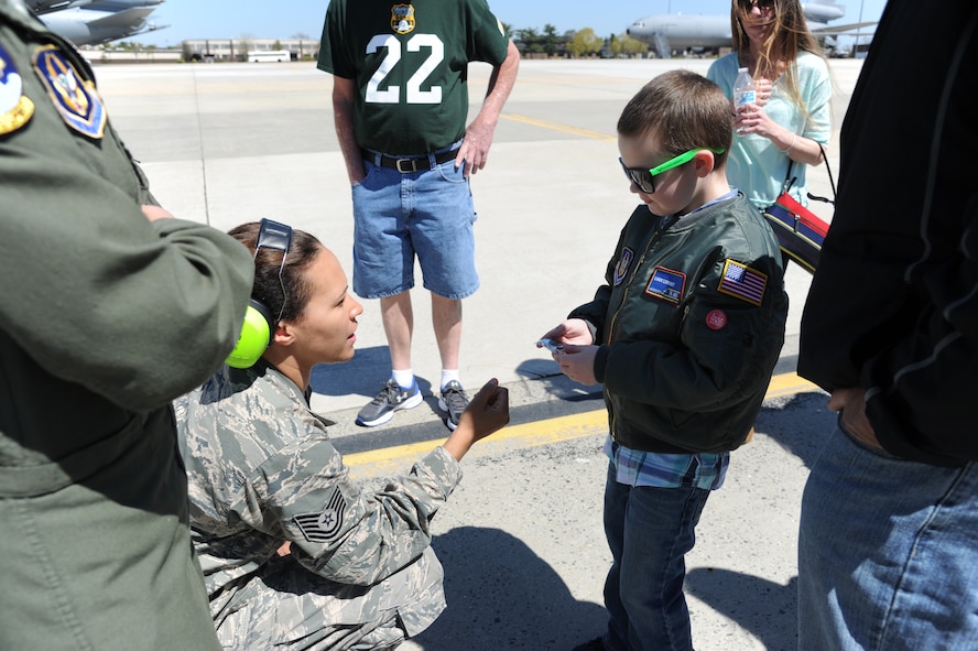 Tech. Sgt. Oshanda Erb, a crew chief with the 714th Aircraft Maintenance Squadron, presents a young cancer patient with a military coin during his visit to the New Jersey joint base to see the KC-10 Extender April 17. Love Your Melon, a non-profit organization run by college students, initiated the tour to the base.