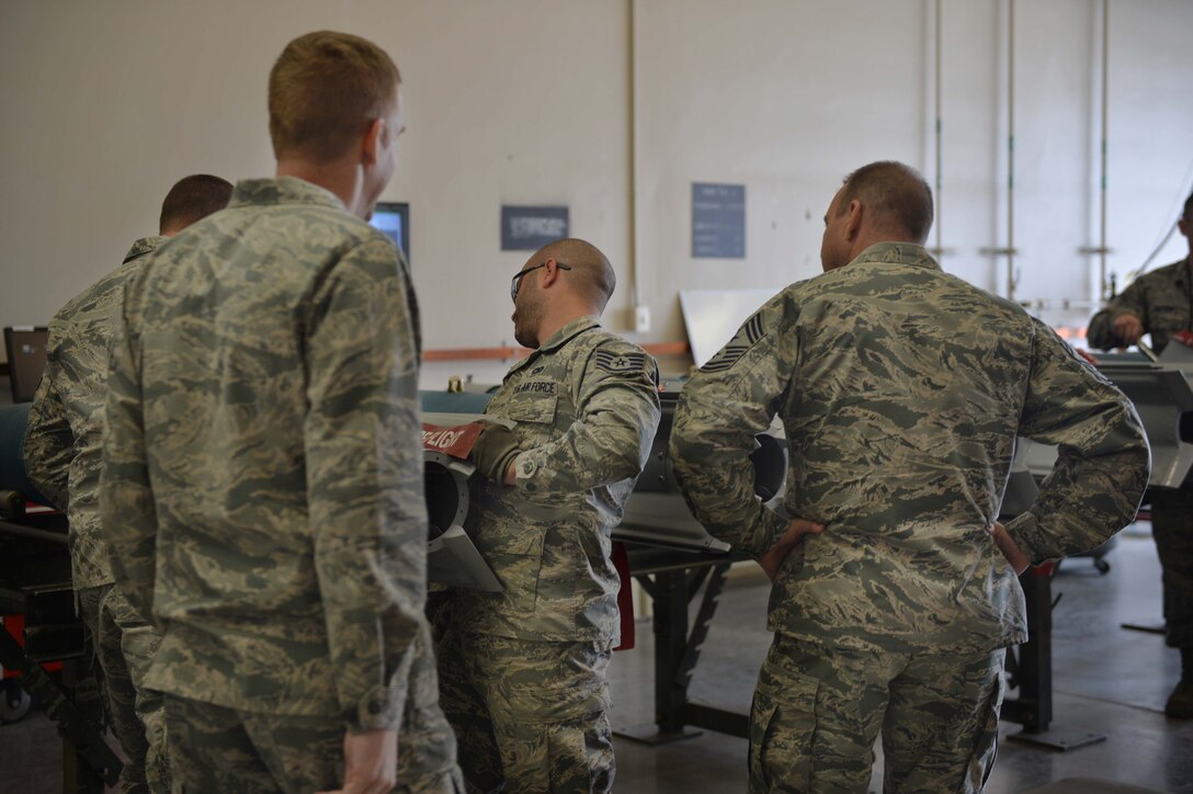 Col. Case Cunningham, 432nd Wing/432nd Air Expeditionary Wing commander, left, and Chief Michael Ditore, 432nd Wg/432nd AEW command chief, right, look on as Staff Sgt. Adam, 432nd Maintenance Squadron munitions flight crew chief, performs maintenance on an inert GBU-12 Paveway ll laser-guided bomb on April 27, 2016, at Creech Air Force Base, Nevada. Cunningham and Ditore assisted the Airmen with building six inert GBU-12 laser-guided bombs to be used for MQ -9 Reaper aircraft training. (U.S. Air Force photo by Airman 1st Class Kristan Campbell/Released).


