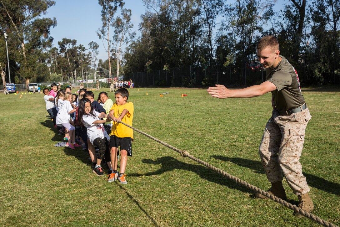 Lance Cpl. Chase McManaman, a volunteer with the Single Marine Program aboard Marine Corps Air Station Miramar, and a Hinton, Okla., native, declares the winner of a tug of war competition at Miramar Ranch Elementary School in San Diego, April 29. The Marines volunteered for a P.E. Fitness Challenge, an event which allowed school-age children and Marines to complete a series of exercises throughout the course of the school day. (U.S. Marine Corps photo by Sgt. Lillian Stephens/Released)