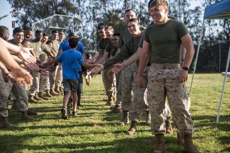 Marines with the Single Marine Program aboard Marine Corps Air Station Miramar give high fives to students at Miramar Ranch Elementary School in San Diego, April 29. The Marines volunteered for a P.E. Fitness Challenge, an event which allowed children and Marines to complete a series of exercises throughout the course of the school day. (U.S. Marine Corps photo by Sgt. Lillian Stephens/Released)