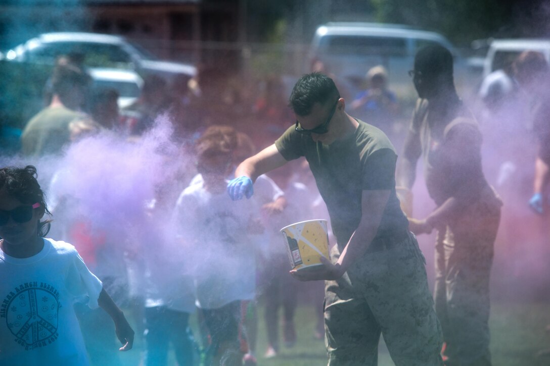 Marines with the Single Marine Program aboard Marine Corps Air Station Miramar toss colored power at the students of Miramar Ranch Elementary School in San Diego, April 29. The Marines volunteered for a P.E. Fitness Challenge, an event which allowed children and Marines to complete a series of exercises throughout the course of the school day. (U.S. Marine Corps photo by Sgt. Lillian Stephens/Released)