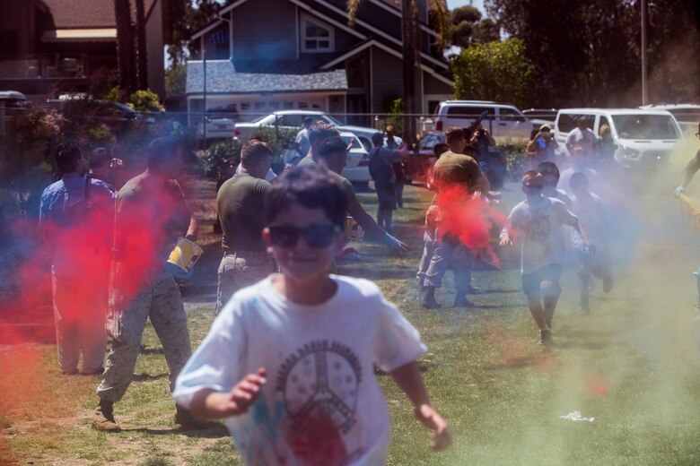 Marines with the Single Marine Program aboard Marine Corps Air Station Miramar toss colored power at the students of Miramar Ranch Elementary School in San Diego, April 29. The Marines volunteered for a P.E. Fitness Challenge, an event which allowed children and Marines to complete a series of exercises throughout the course of the school day. (U.S. Marine Corps photo by Sgt. Lillian Stephens/Released)