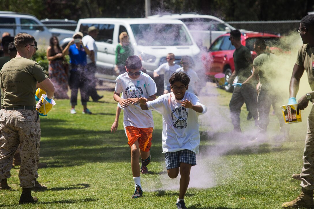 Marines with the Single Marine Program aboard Marine Corps Air Station Miramar toss colored power at the students of Miramar Ranch Elementary School in San Diego, April 29. The Marines volunteered for a P.E. Fitness Challenge, an event which allowed children and Marines to complete a series of exercises throughout the course of the school day. (U.S. Marine Corps photo by Sgt. Lillian Stephens/Released)