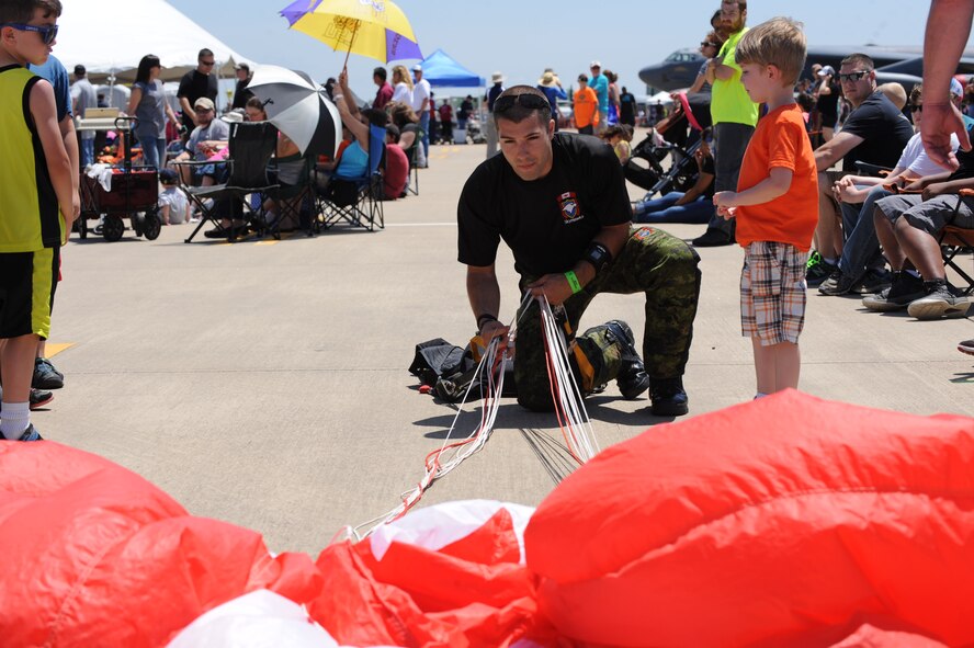 A member of the Canadian SkyHawks team shows children how he folds his parachute during the 2016 Defenders of Liberty Airshow at Barksdale Air Force Base, La., April 30. The SkyHawks are the Canadian Armed Forces parachute demonstration team and have done more than 5,000 successful jumps. (U.S. Air Force photo/Airman Alexis C. Frost)