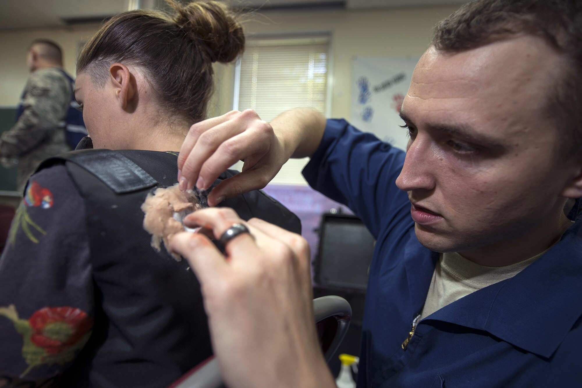 U.S. Air Force Staff Sgt. Justin Rhodes, a lab technician with the 18th Dental Squadron applies moulage makeup to a simulated gunshot wound victim, at Kadena Air Base, Japan, before an active shooter exercise May 4, 2016. In a push to better prepare the 18th Wing’s Airmen, recent exercises have given Airmen here little to no warning before unfolding into often gruesome or stressful circumstances.  (U.S. Air Force photo by Staff Sgt. Maeson L. Elleman/Released)
