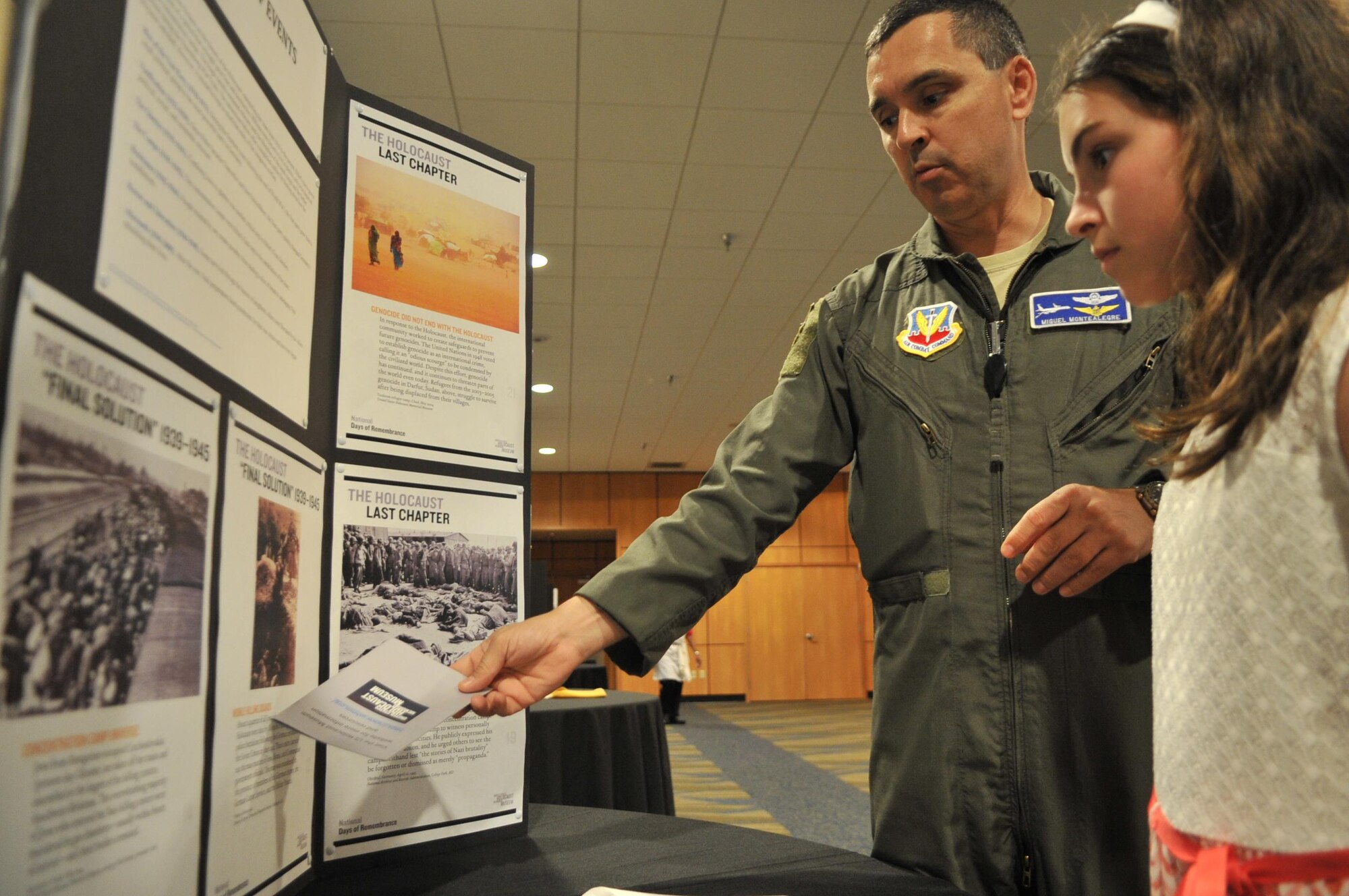 Lt. Col. Luis Montealegre, 1st Air Force A9 deputy director, reads holocaust information with his daughter Cristina Montealegre during the Holocaust Remembrance Day event May 4 at the Horizons Community Center. The event is also known in the Hebrew language as Yom Hashoah. The day corresponds with the 27th day of Nisan on the Hebrew calendar which means the day falls on different days of the year within the standard 365 day calendar year. (U.S. Air Force photo by Senior Airman Ty-Rico Lea/Released)
