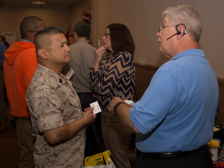 Keith L. Schurkus, Georgia Pacific representative, talks to Gunnery Sgt. Arnel Narvaez, hazardous materials chief, 1st Tank Battalion, about sustainable cloth during the Combat Center’s Sustainability Expo at the Frontline Restaurant April 26, 2016. (Official Marine Corps photo by Cpl. Connor Hancock/Released)