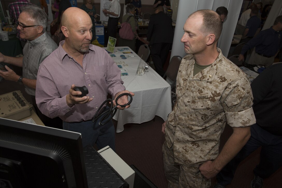 Ken King, manager, Western Area Research Test and Evaluation Center, Naval Facilities Engineering Command, shows communication components to Maj. Jamisen Fox, operations and plans officer, Marine Air Ground Task Force Training Command, during the Combat Center’s Sustainability Expo at the Frontline Restaurant April 26, 2016. (Official Marine Corps photo by Cpl. Connor Hancock/Released)