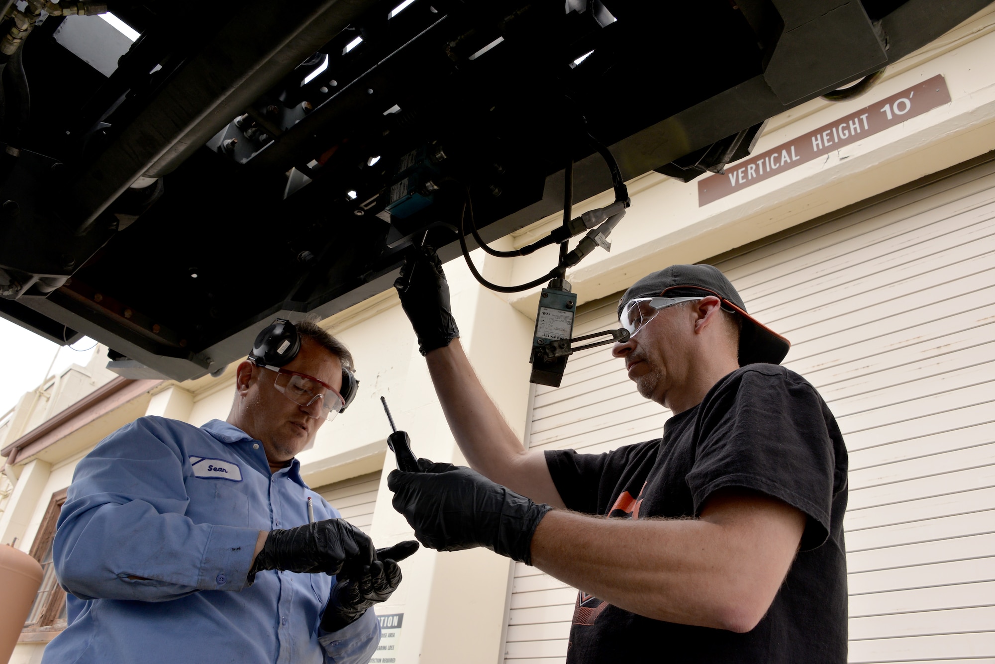 Sean O’Leary, left, and Michael Dickie, right, both from the 60th Logistics Readiness Squadron install a limit switch on an aircraft cargo loader April 26, 2016, at Travis Air Force Base, California. (U.S. Air Force photo by Staff Sgt. Charles Rivezzo)