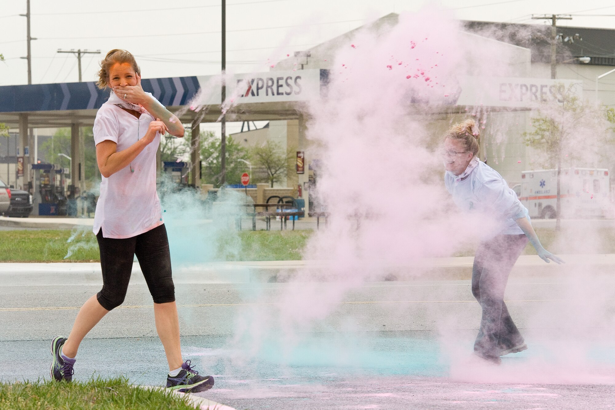 Senior Airmen Colleen Windsor, right, course volunteer for the 5K Color Run, tosses colored powder on Brandy Ousley, wife of Senior Master Sgt. Steven Ousley, 436th Aerial Port first sergeant, near the finish line, April 28, 2016, on Dover Air Force Base, Del. Volunteers dusted most of the 81 runners with colored powder throughout the 3.1 mile course. (U.S. Air Force photo/Roland Balik)