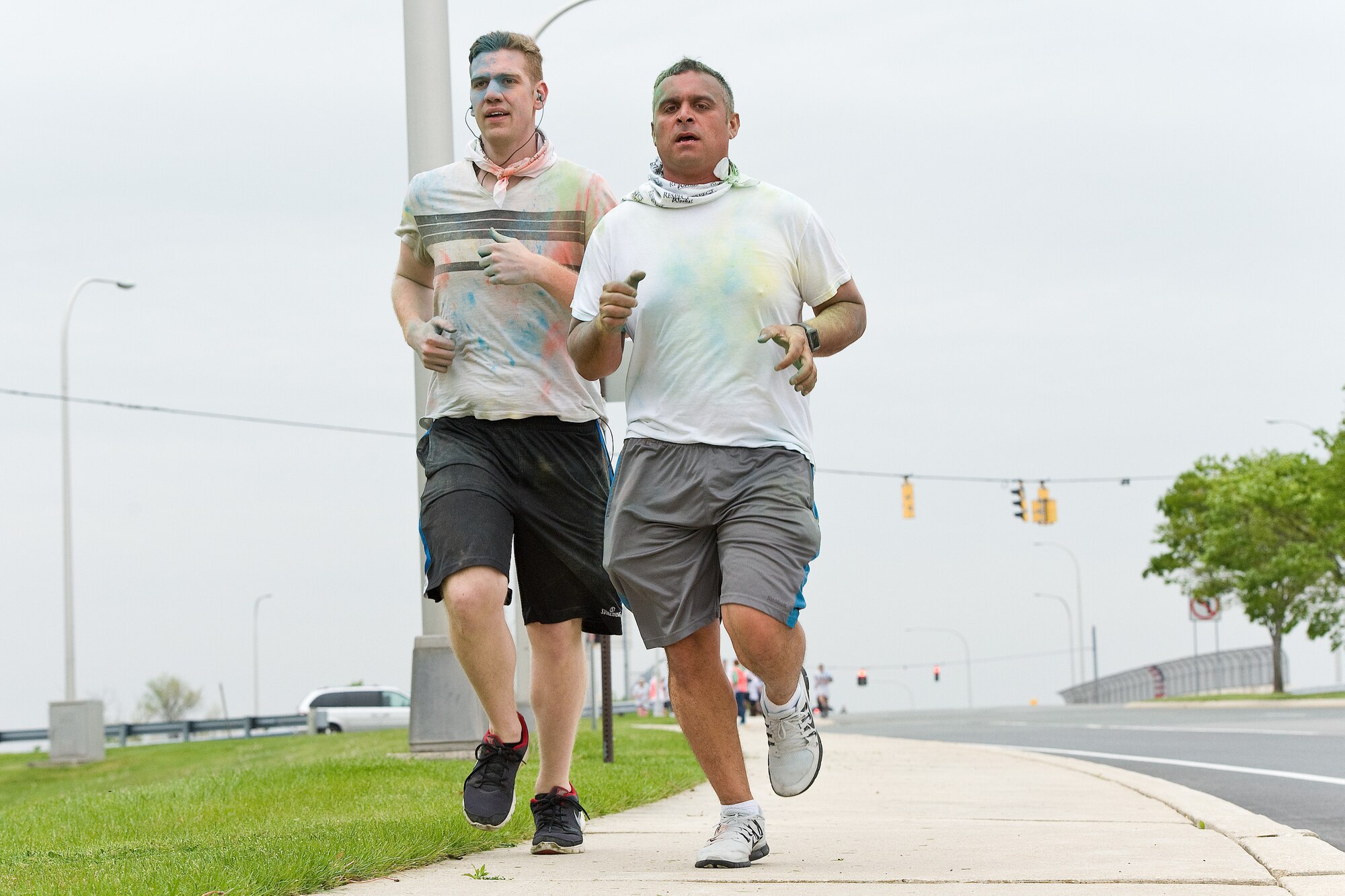 Senior Airman Scott Luhn, left, and Tech. Sgt. Xavier Maldonado, right, both 9th Airlift Squadron loadmasters, run toward the main gate during the Sexual Assault Awareness Month 5K Color Run, April 28, 2016, on Dover Air Force Base, Del. The Color Run was the last event held during Sexual Assault Awareness Month. (U.S. Air Force photo/Roland Balik)