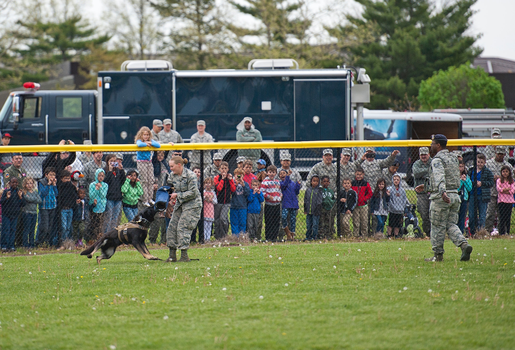 Iley, a five year old black German Shephard military working dog with the 87th Security Forces Squadron, apprehends Senior Airman Ashlee Blandford, 87th SFS handler, as spectators watch at a K9 demonstration during the base's bring your child to work day April 28. (U.S. Air Force photo by Christian DeLuca/released)