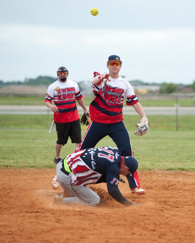 A member of the Swing Kingz softball team throws the ball to first base after tagging the runner out at second base during the 2nd Annual Kings of the Bay Softball Tournament at Langley Air Force Base, Va., April 30, 2016. The softball tournament held a cornhole tournament, as well as a homerun derby to fundraise for the 30th Intelligence Squadron. (U.S. Air Force photo by Airman 1st Class Kaylee Dubois)