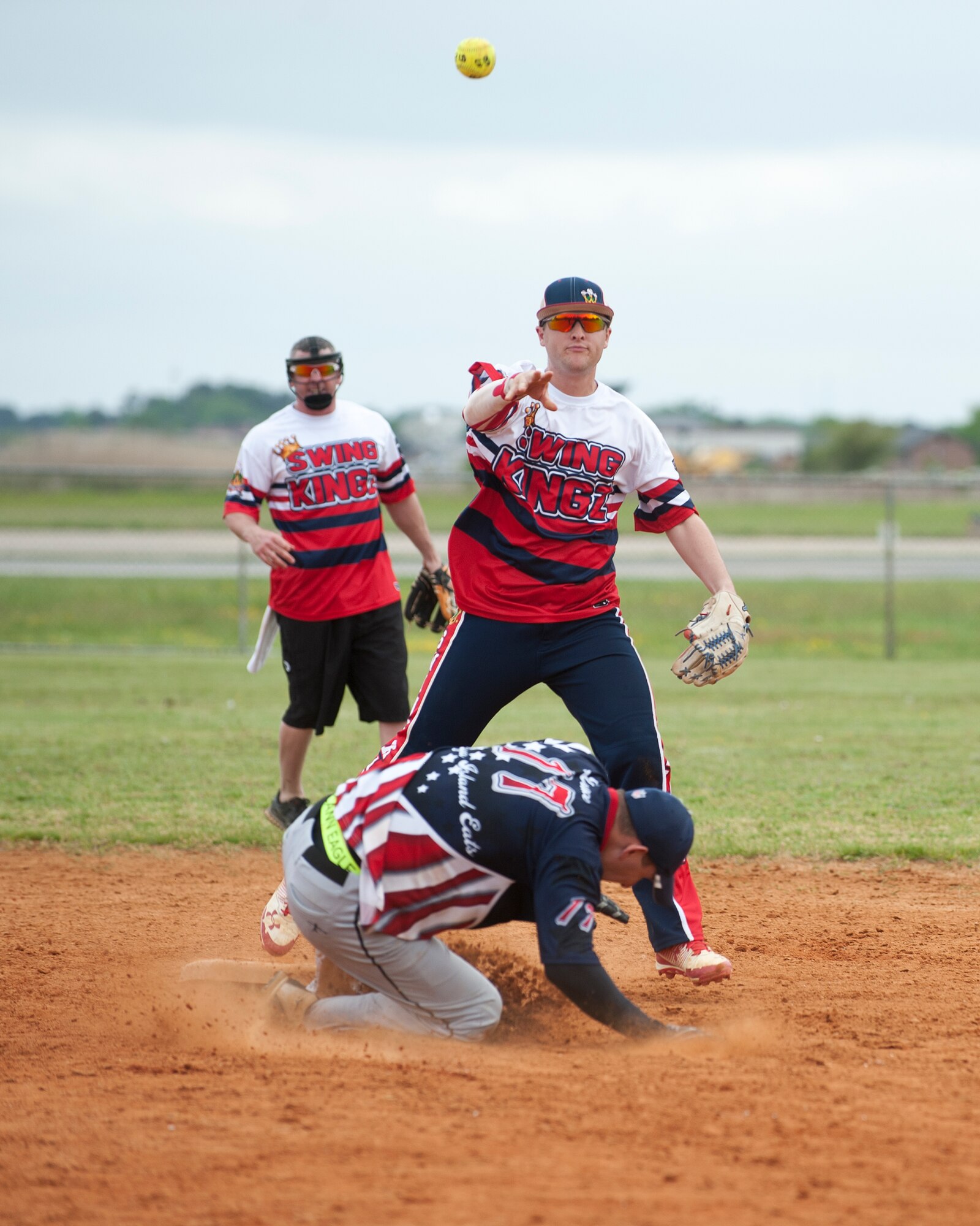 A member of the Swing Kingz softball team throws the ball to first base after tagging the runner out at second base during the 2nd Annual Kings of the Bay Softball Tournament at Langley Air Force Base, Va., April 30, 2016. The softball tournament held a cornhole tournament, as well as a homerun derby to fundraise for the 30th Intelligence Squadron. (U.S. Air Force photo by Airman 1st Class Kaylee Dubois)