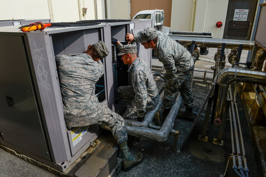 A team of 18th Civil Engineer Squadron heating, ventilation and air conditioning technicians work to fix a condensor fan that pulls hot air out of a building, April 28, 2016, at Kadena Air Base, Japan. The workload for the HVAC shop triples this time of year at the start of summer because it is the peak time for air conditioning breakdowns. (U.S. Air Force photo by Senior Airman Stephen G. Eigel)