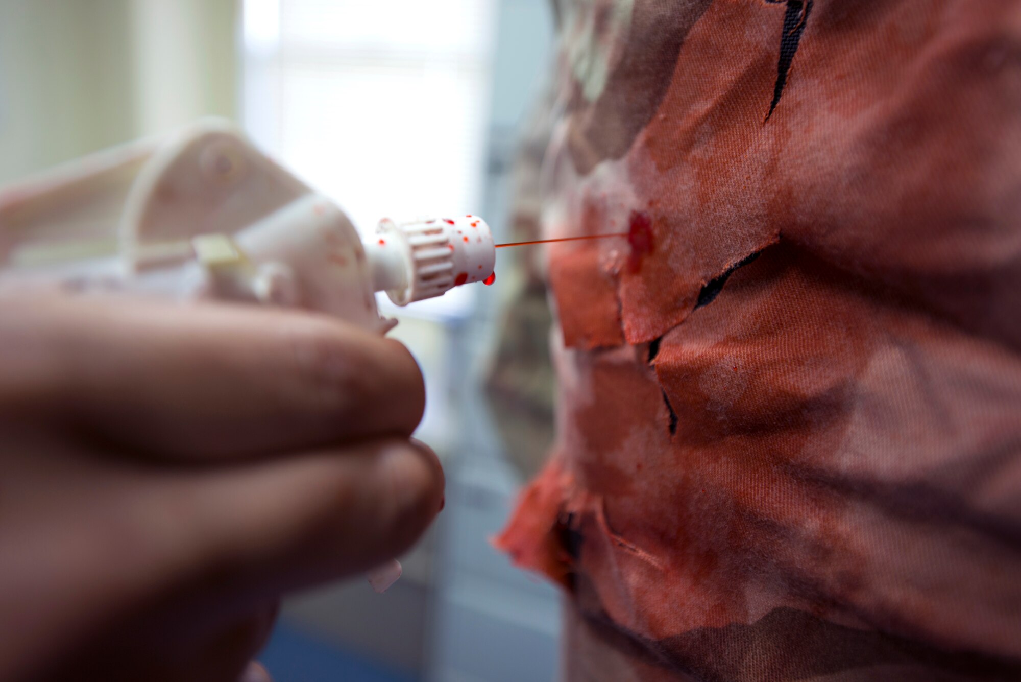 U.S. Air Force Staff Sgt. Brian Reyes, 18th Dental Squadron lab technician adds fake blood to a soon-to-be simulated gunshot wound victim’s uniform before an active shooter exercise May 4, 2016, at Kadena Air Base, Japan. Using makeup and simulated blood adds realism to exercise scenarios, providing stronger training to emergency responders. (U.S. Air Force photo by Staff Sgt. Maeson L. Elleman)