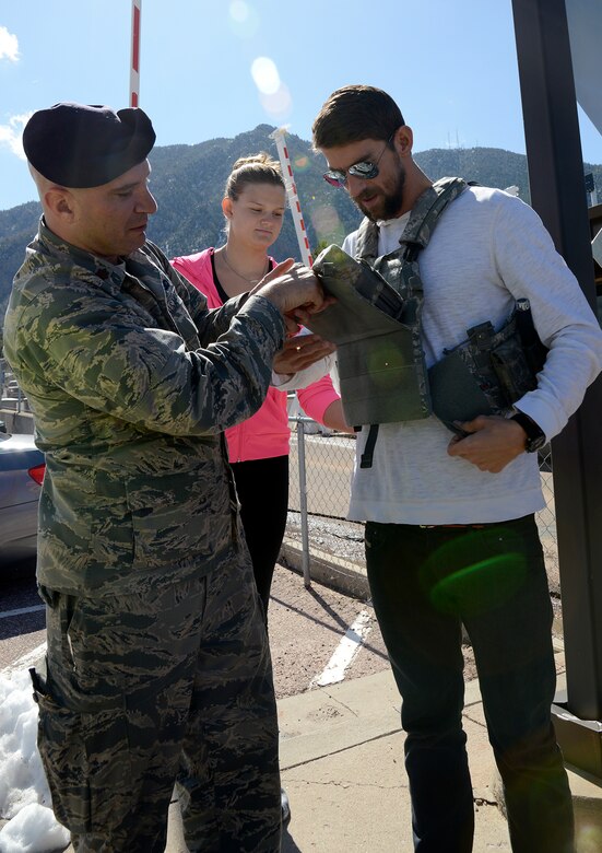 CHEYENNE MOUNTAIN AIR FORCE STATION, Colo. – Olympic Gold Medalist Michael Phelps is helped by Maj. Kevin Lombardo, 721st Security Forces commander, trying on body armor during a visit May 2, 2016. The swimmers toured the Mountain, signed autographs and posed for pictures with the service members “Behind the Blast Doors”. The visit was part of the ongoing 50th Anniversary celebration for the Mountain. (U.S. Air Force photo by Master Sgt. Jared Marquis)