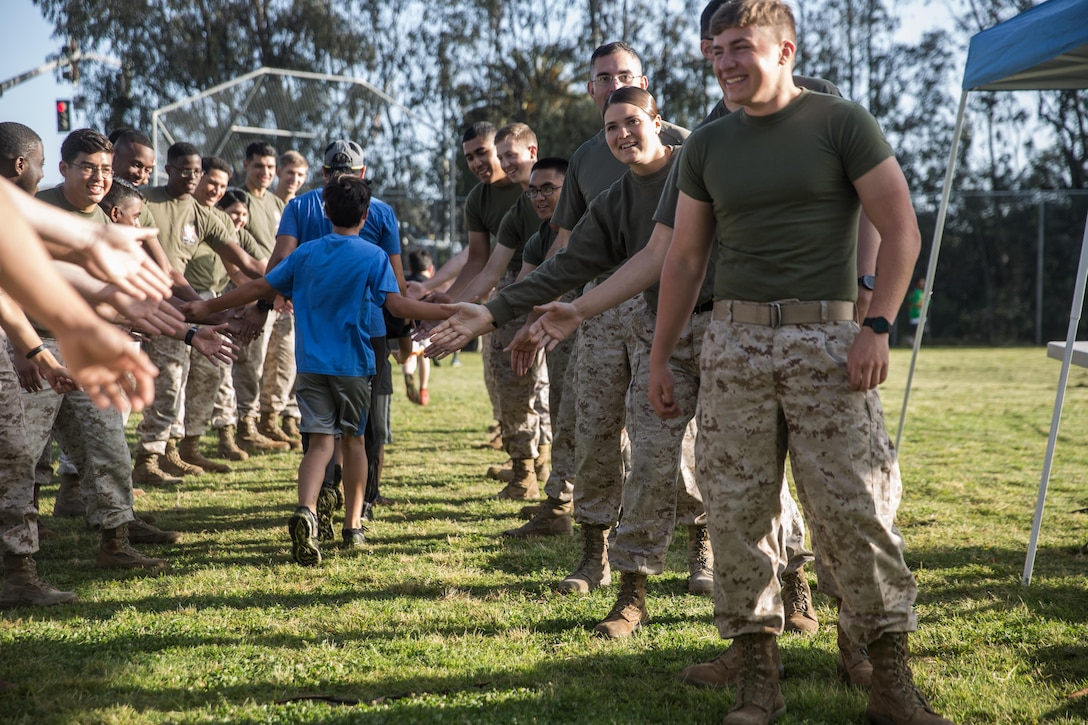 Marines with the Single Marine Program aboard Marine Corps Air Station Miramar give high fives to students at Miramar Ranch Elementary School in San Diego, April 29. The Marines volunteered for a P.E. Fitness Challenge, an event which allowed children and Marines to complete a series of exercises throughout the course of the school day. (U.S. Marine Corps photo by Sgt. Lillian Stephens/Released)