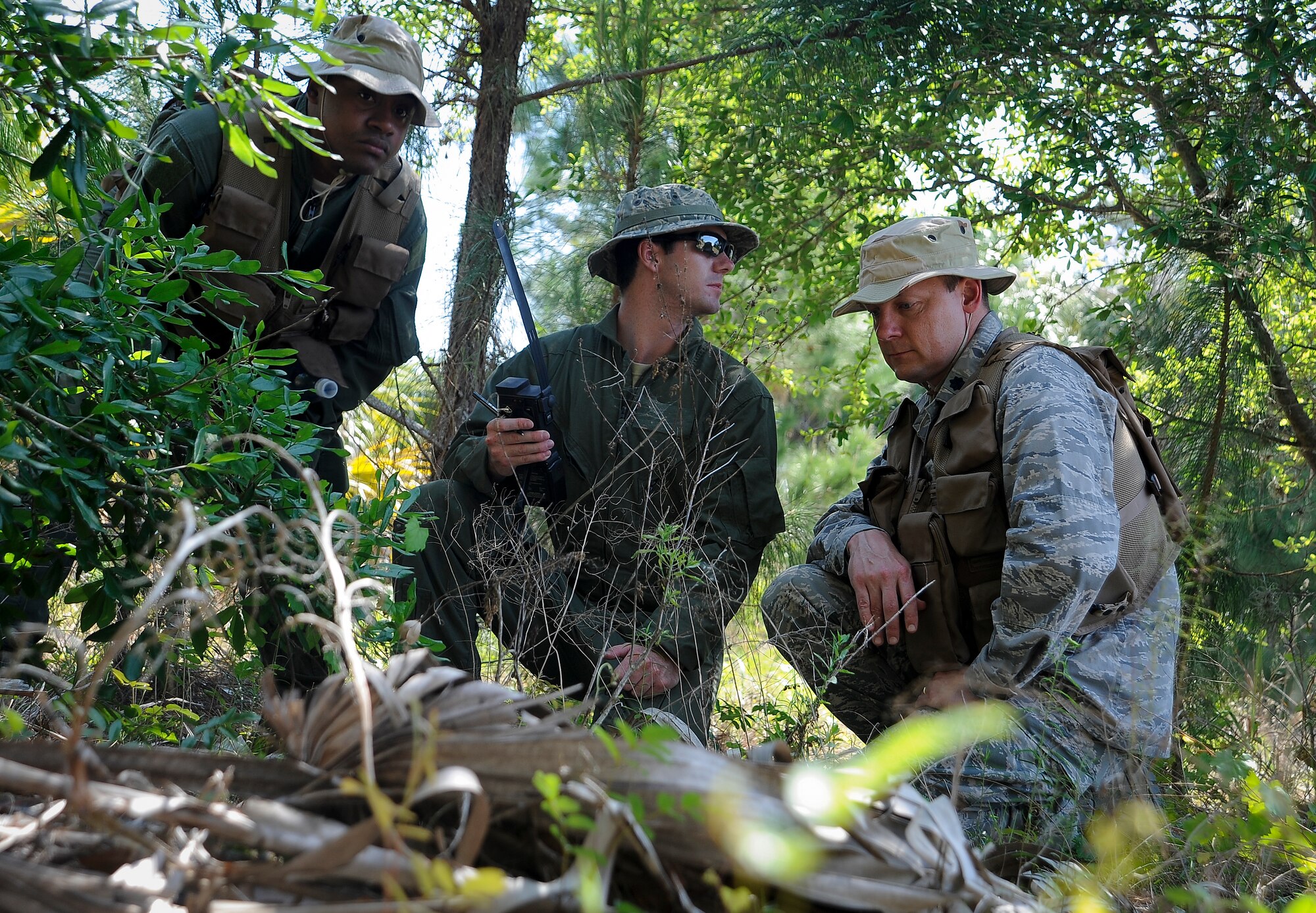 Aircrew members from various squadrons listen to the radio as they hide from oppositional forces during combat survival training at MacDill Air Force Base, Fla., April 27, 2016. During the training, Airmen were tasked to set up a radio signal, evade oppositional forces and meet at a location for rescue. (U.S. Air Force photo by Airman 1st Class Mariette Adams)