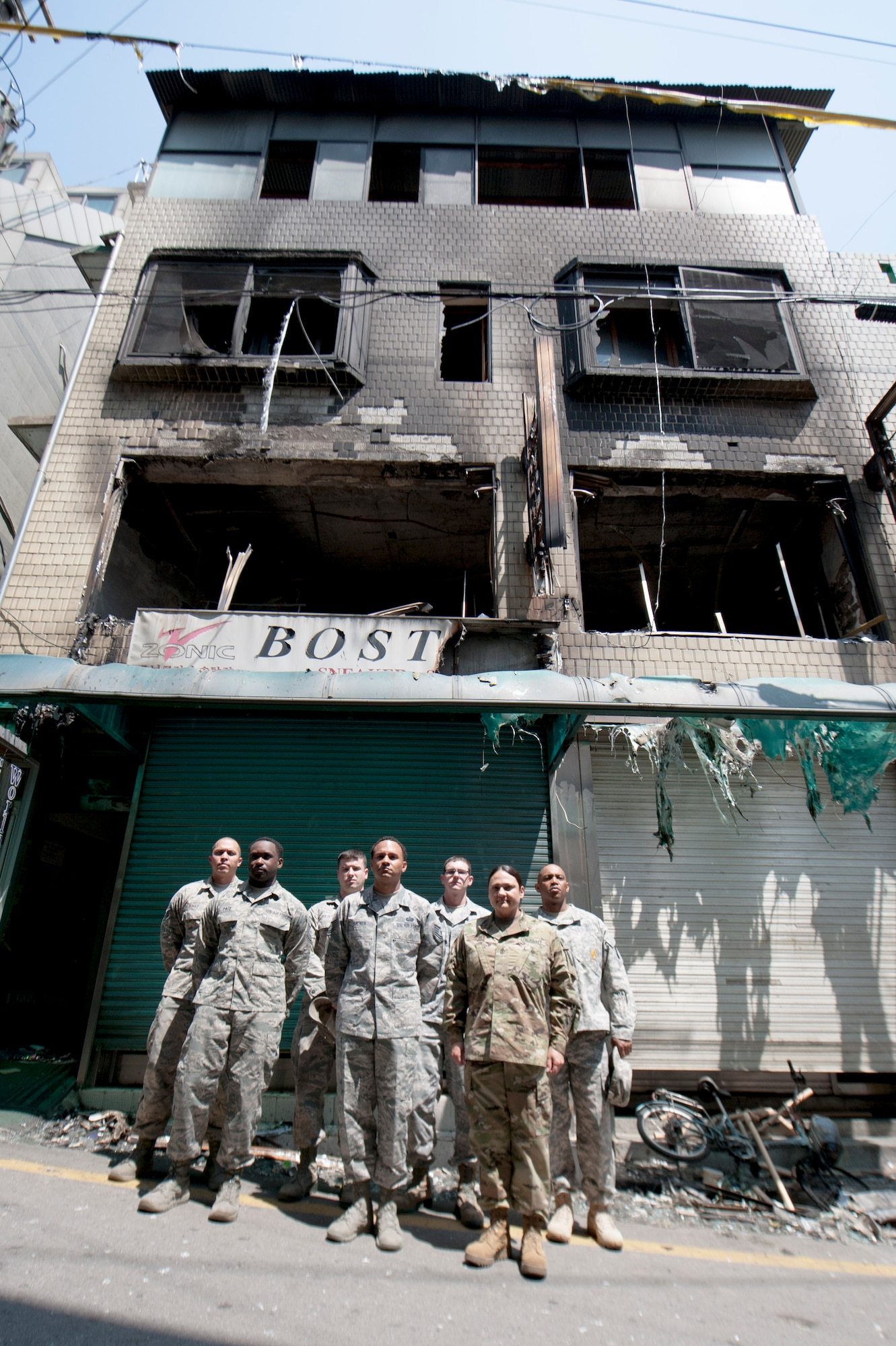 Team Osan members pose near the building that caught fire in the Songtan shopping district, Republic of Korea, May 2, 2016. The Airmen and Soldiers, along with many onlookers worked together to save the lives of an Airman, a mother and her three children when a fire broke out on April 29, 2016. (U.S. Air Force photo by Staff Sgt. Jonathan Steffen/Released