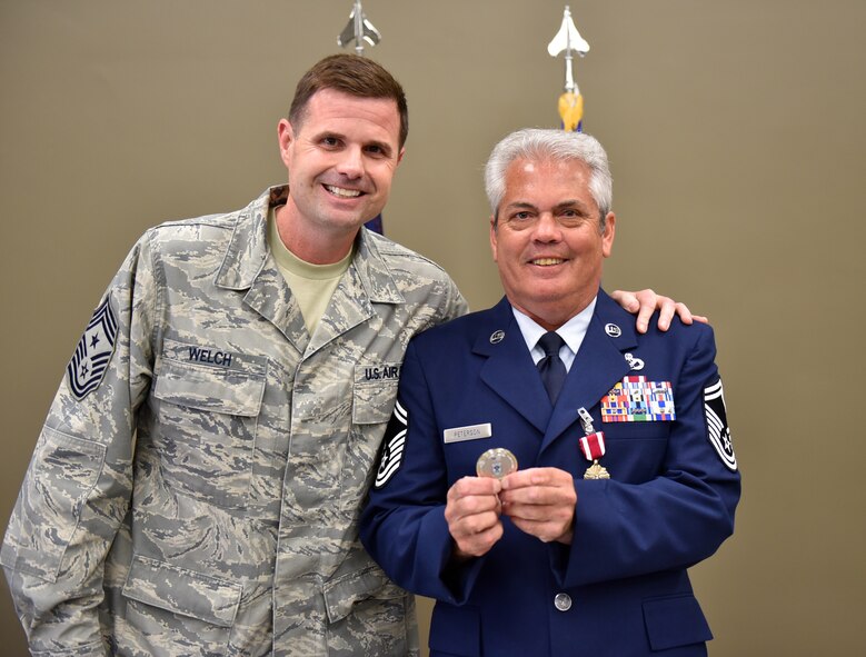 Command Chief Master Sgt. Chad Welch presented his special "chief's" coin of recognition to retiring Senior Master Sgt. Ronald Peterson at his retirement celebration event on May 1, 2016 at the 932nd Airlift Wing.  After the event Peterson said on future drill weekends, "I'm going to watch the kids play more ball now."  He will still be seen out at the Illinois unit as the facility manager during the week.  (U.S. Air Force photo by Tech. Sgt. Christopher Parr)