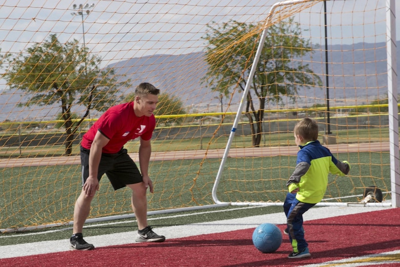 Lance Cpl. Kyle Cavatorta, tank crewman loader, 1st Tank Battalion, plays soccer with Noah Klich, 7, son of Staff Sgt. Mitchell A. Klich, technical control chief, Marine Corps Communication-Electronics School at the Healthy Kids Day hosted by Armed Services YMCA at Felix Field aboard the Combat Center April 30, 2016.  (Official Marine Corps photo by Lance Cpl. Dave Flores/Released)