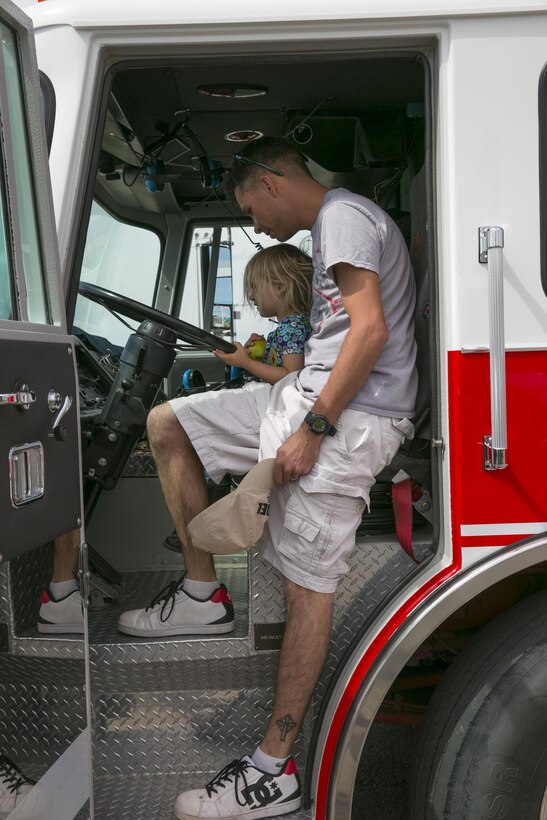 Sgt. Jeffery Walsh, roleplayer, Tactical Training Exercise Control Group, and his daughter Genevieve Walsh, 3, sit in the driver’s seat of a Combat Center firetruck during the Healthy Kids Day hosted by the Armed Services YMCA at Felix Field aboard the Combat Center April 30, 2016. (Official Marine Corps photo by Lance Cpl. Dave Flores/Released)