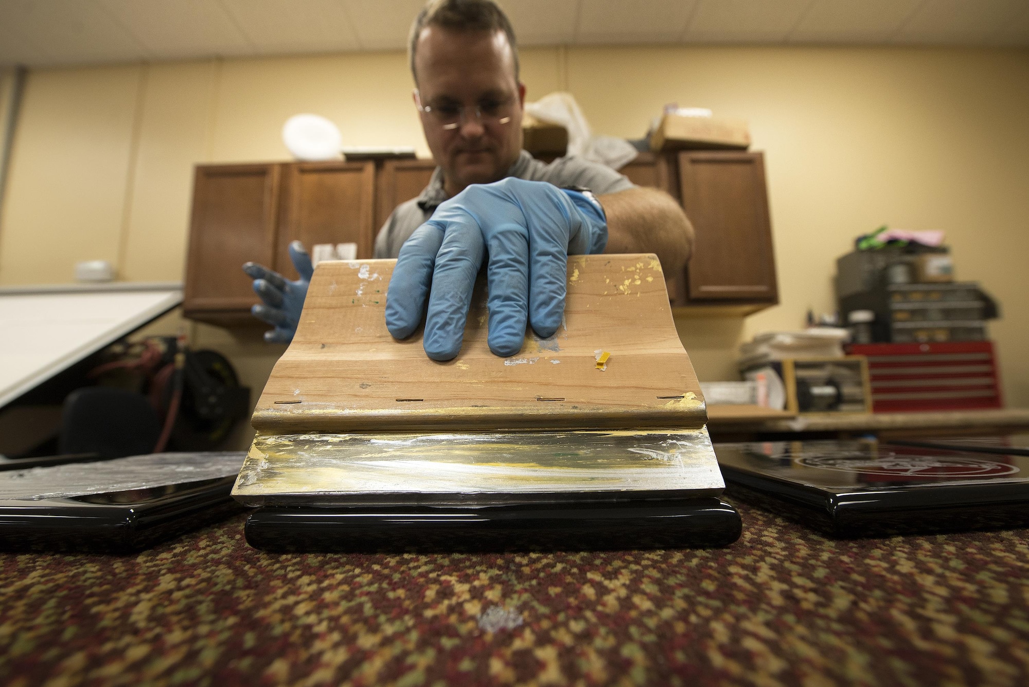 Daniel Bak, 23d Force Support Squadron recreation assistant, paints an award after engraving it, May 4, 2016, at Moody Air Force Base, Ga. The plaque and frame section of The Shop engraves and paints all of the awards given on base. (U.S. Air Force photo by Airman 1st Class Janiqua P. Robinson/Released)