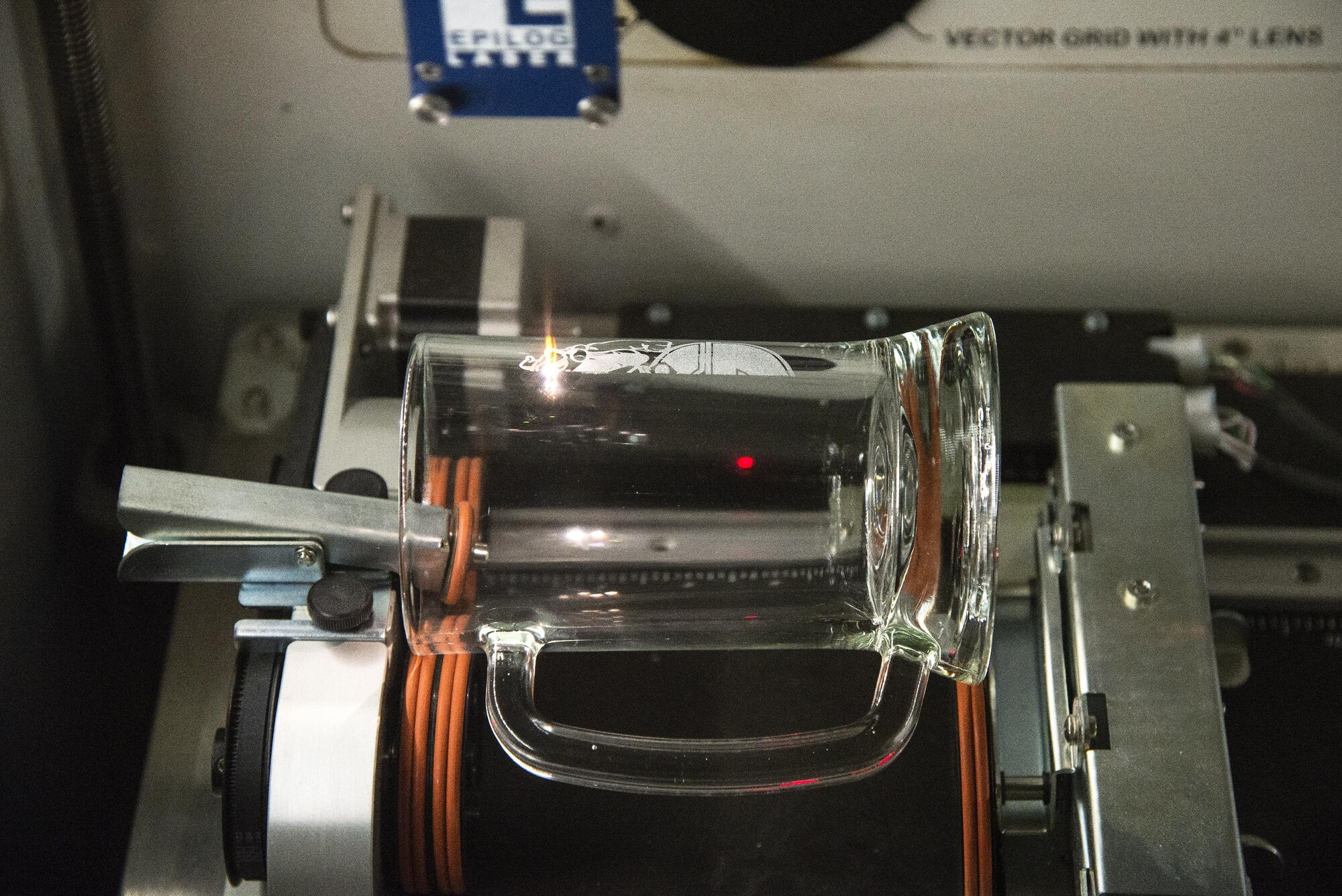 A laser fusion system engraves a sports symbol into a mug, May 4, 2016, at Moody Air Force Base, Ga. The plaque and frame section of The Shop is able to engrave multiple symbols on the same mug because the laser fusion system can turn the mug as it engraves. (U.S. Air Force photo by Airman 1st Class Janiqua P. Robinson/Released)