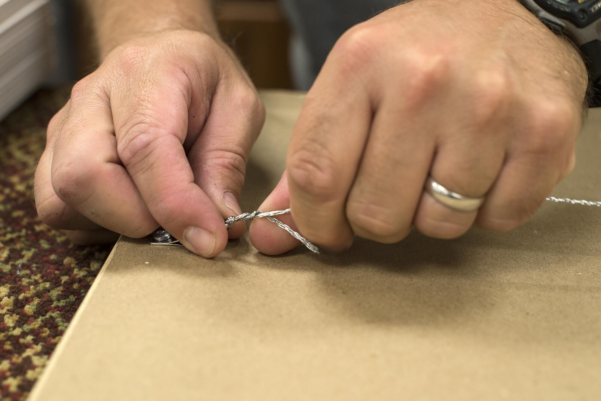 Daniel Bak, 23d Force Support Squadron recreation assistant, attaches hanging wire to a picture frame, May 4, 2016, at Moody Air Force Base, Ga. To frame a photo, Bak cuts and cleans the glass, places a foam board on top of the photo to hold it in place, tapes construction paper to the back, and attaches hanging mechanisms. (U.S. Air Force photo by Airman 1st Class Janiqua P. Robinson/Released)