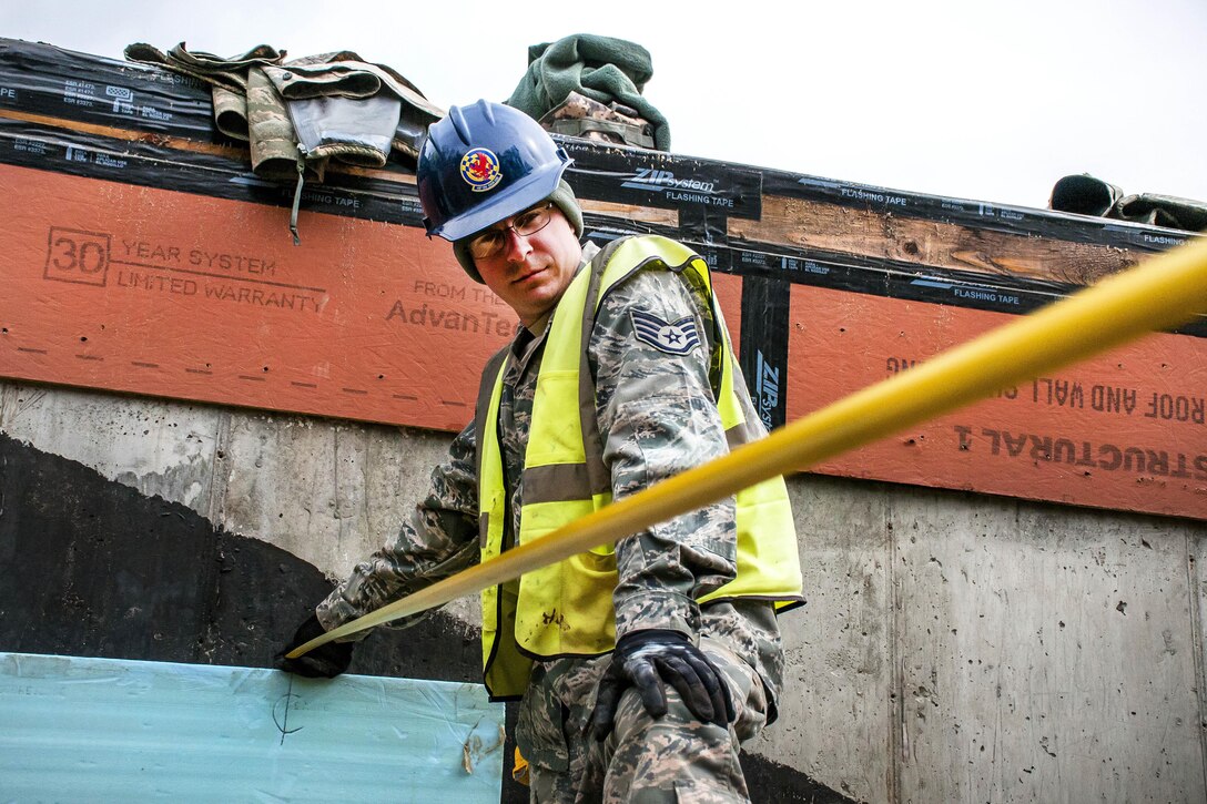 Air Force Staff Sgt. Casey Nowicki holds a tape measure to help calculate where to put molding tubes to pour concrete at Camp Hinds in Raymond, Maine, May 3, 2016. Nowicki is a structural craftsman assigned to the 110th Attack Wing Civil Engineering Squadron. The unit participated in Innovative Readiness Training, which helps airmen achieve wartime readiness while assisting the community. Air National Guard photo by Airman Tiffany Clark