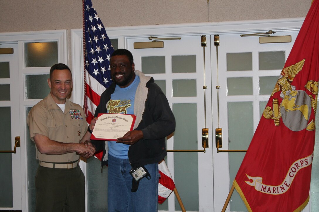 Col. Joseph Murray, Marine Corps Base Quantico commander, presents Brandon Lloyd, a motor vehicle operator with the base Installation and Environment Division, with his award for Junior Civilian of the Quarter for the first quarter of 2016 at a ceremony held at The Clubs at Quantico April 28. Lloyd was commended for his hard work clearing the base of snow after three major snow events this winter.