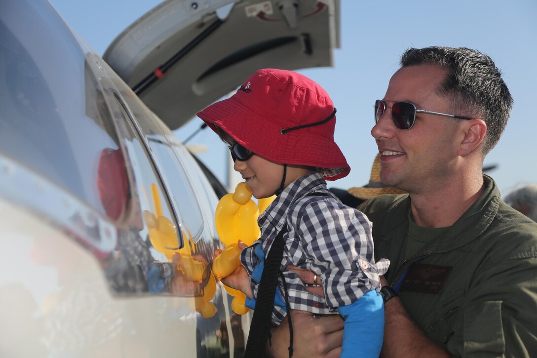 A service member raises a Japanese child to see through the windows of an aircraft during the Marine Corps Air Station Iwakuni Friendship Day 2016 Air Show, Japan, May 5, 2016. The air station has hosted a single-day air show and open house since 1973 to foster positive relationships with residents. Marine Corps photo by Lance Cpl. Christian Robertson