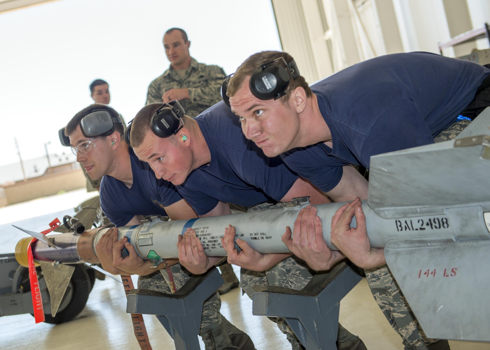 From left to right: Senior Airman Caleb, Staff Sgt. Josh and Senior Airman Matthew, 54th Fighter Group weapons load crew members from Holloman Air Force Base, N.M., lift a training missile during the annual load competition here May 4. Teams from the 54th Fighter Group and the 49th Aircraft Maintenance Squadron here competed by testing their ability to quickly load training weapon systems onto their respective aircraft. (Last names are withheld due to operational requirements) (U.S. Air Force photo by Airman 1st Class Randahl J. Jenson)  