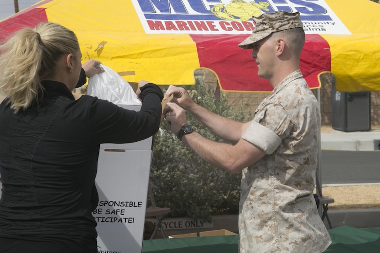 Staff Sgt. Joshua Gerland, physical security chief, Provost Marshal’s Office, helps a Combat Center patron dispose of their prescription medications during the PMO Prescription Drug Take Back held at the base exchange parking lot April 30, 2016. (Official Marine Corps photo by Cpl. Thomas Mudd/Released)