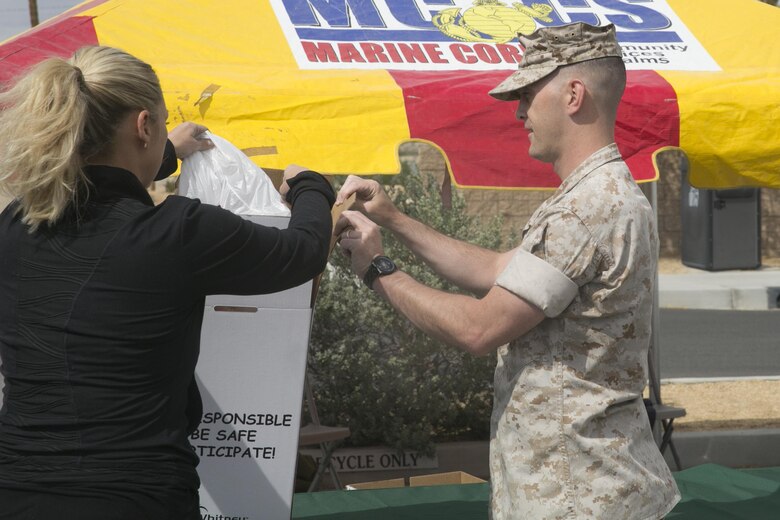 Staff Sgt. Joshua Gerland, physical security chief, Provost Marshal’s Office, helps a Combat Center patron dispose of their prescription medications during the PMO Prescription Drug Take Back held at the base exchange parking lot April 30, 2016. (Official Marine Corps photo by Cpl. Thomas Mudd/Released)