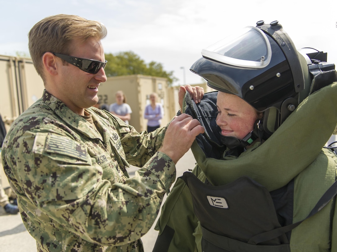 Navy Explosive Ordnance Disposal Technician 3rd Class Erik Kastner, assigned to EOD Mobile Unit 6, helps a student from the Civic Leadership Institute of Hampton Roads don an EOD Mark 9 bomb suit during a tour April 21 at Joint Expeditionary Base Little Creek, Virginia. DLA Troop Support provides equipment to EOD customers through its Construction and Equipment supply chain. 