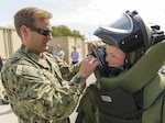 Navy Explosive Ordnance Disposal Technician 3rd Class Erik Kastner, assigned to EOD Mobile Unit 6, helps a student from the Civic Leadership Institute of Hampton Roads don an EOD Mark 9 bomb suit during a tour April 21 at Joint Expeditionary Base Little Creek, Virginia. DLA Troop Support provides equipment to EOD customers through its Construction and Equipment supply chain. 