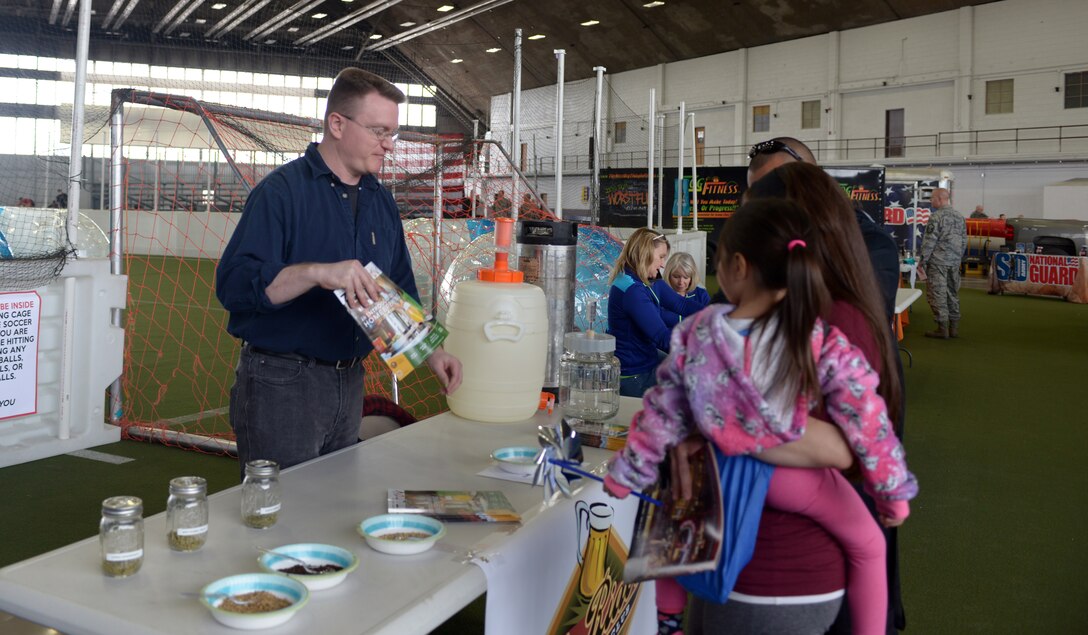 Matthew Kranitz, a representative of the Ale Riders Homebrewing Club, talks to a family at the Pride Hangar during the Discover the Hills portion of Wingman and Spouse Appreciation Day at Ellsworth Air Force Base, S.D., April 29, 2016. Throughout the event, organizations from across the Black Hills hosted booths and answered questions from Airmen and family members. (U.S. Air Force photo by Airman Donald Knechtel/Released)