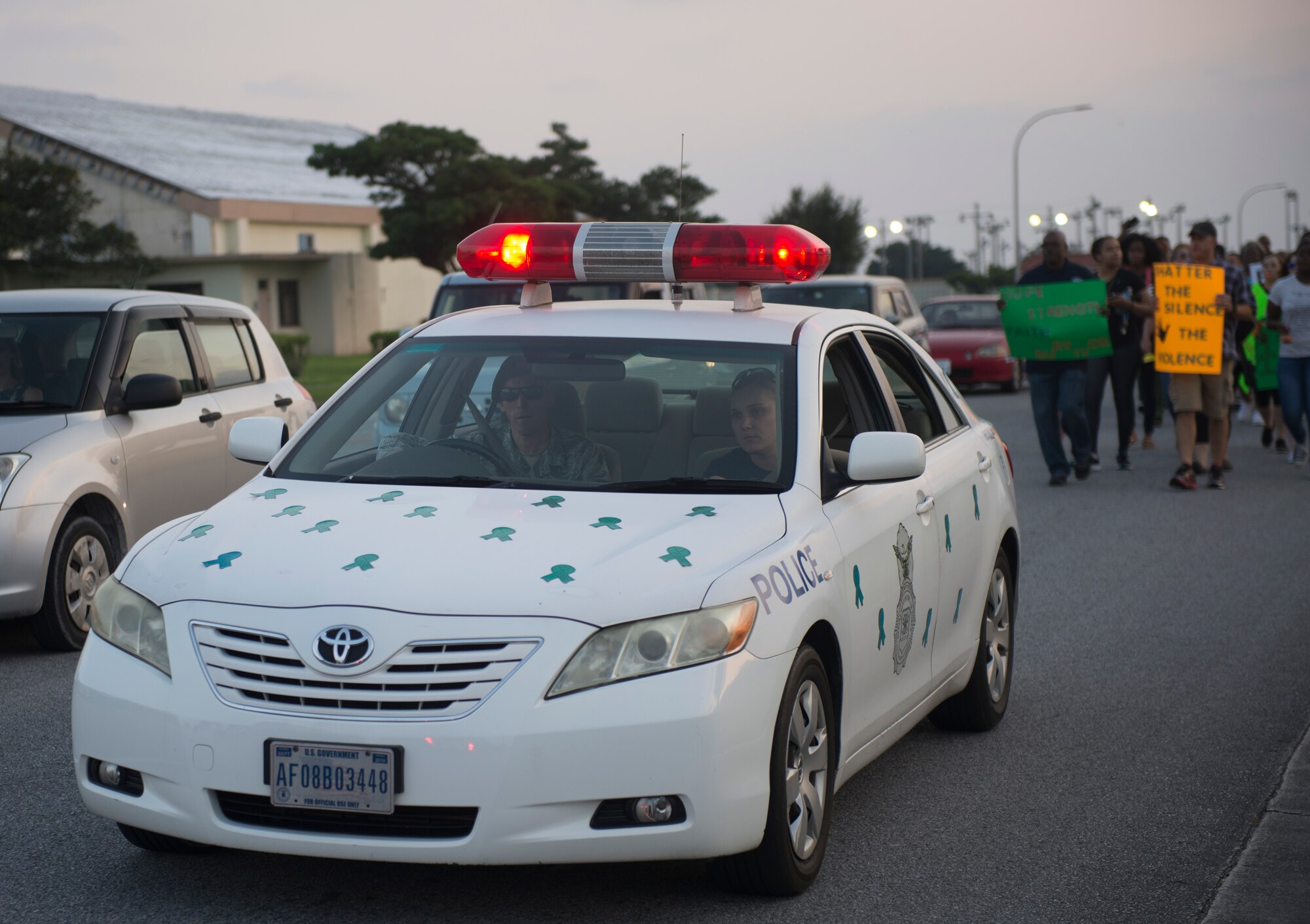 An 18th Wing Security Forces patrol car decorated in teal ribbons leads the Take Back the Night march April 29, 2016, at Kadena Air Base, Japan. The participants marched from the Schilling Community Center parking lot toward Chapel 2 with noise makers and cowbells while chanting, symbolizing survivors reclaiming the night, the time when sexual assaults are most likely to occur. (U.S Air Force photo by Senior Airman Omari Bernard)