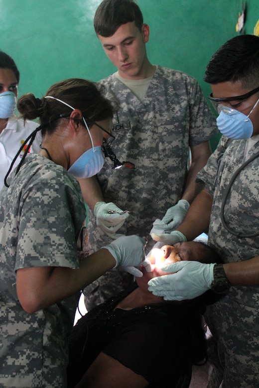 U.S. Army Maj. Margaret Novicio (left), Joint Task Force-Bravo Medical Element, is assisted by U.S. Army Corporal Tyler Novich (center), and U.S. Army Specialist Jeffry Gomez (right), while performing a tooth extraction on a Honduran woman during a Medical Readiness Training Exercise in Ostumán, Copán, Honduras, April 28,2016. Dental care is one of many services provided during a MEDRETE, which also includes an initial health class, basic medical attention and pharmacy.  (U.S. Army photo by Maria Pinel)