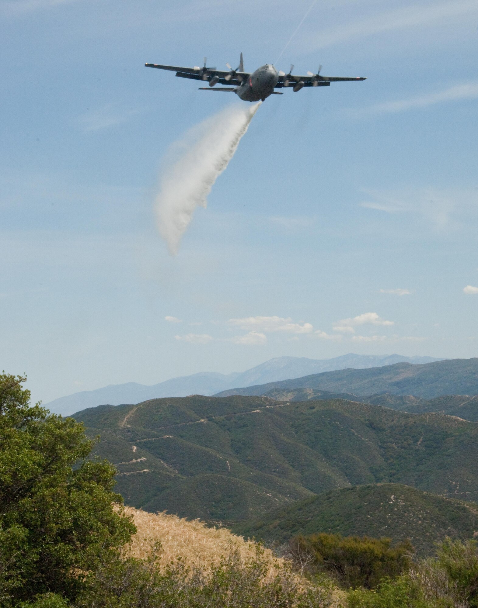 A line of water is dropped high above the Los Angeles Forest from a Air National Guard C-130 containing the MAFFS (Modular Airborne Firefighting System) system used to combat wild fires during annual MAFFS training on May 3 2016. (U.S. Air National Guard photo by Staff Sgt. Nicholas Carzis)