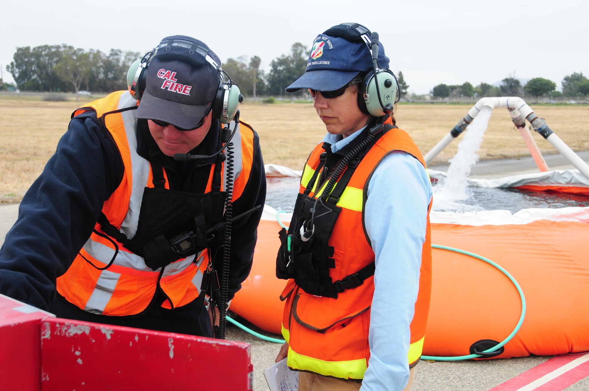 Assistant Air Base Fueler from the Santa Maria Air Tanker Base Elena Rios with U.S. Forest Service and CAL FIRE Firefighter, Peter Hardy, from Paso Robles Air Tanker Base, monitor water that is being pumped into a MAFFS unit on a C-130 airtanker during training at the 146th Airlift Wing in Port Hueneme, California on May 4, 2016. Air National Guard and Reserve units from across the U.S. convened for MAFFS (Modular Airborne Fire Fighting Systems)annual certification and training this week to prepare for the upcoming fire season in support of U.S. Forest Service. (U.S. Air National Guard Photo by Senior Airman Madeleine Richards/Released)