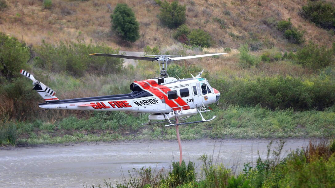 An aircraft hovers over water at the Wildland Firefighting Exercise 2016 hosted by Marine Corps Base Camp Pendleton  at Las Pulgas Lake, May 5, 2016. The Wildland Firefighting Exercise 2016 combines elements of aviation and ground units from Marine Corps Base Camp Pendleton, 3rd Marine Air Wing, Navy Region Southwest, The California Department of Forestry and Fire Protection, and the San Diego's Sheriff's Department.