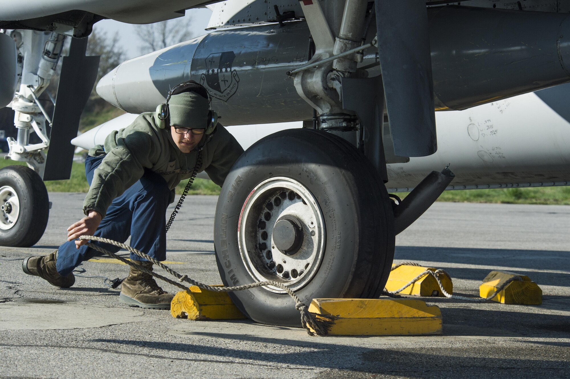 U.S. Air Force Airman 1st Class Jacob Johnson, 74th Expeditionary Fighter Squadron crew chief, removes the blocks from the wheels of an A-10 Thunderbolt II during the 74th EFS’s deployment in support of Operation Atlantic Resolve at Graf Ignatievo, Bulgaria, March 18, 2016. Johnson and his fellow 74th EFS crew chiefs ensure all aircraft are prepared and safe for flight before and after each flight. (U.S. Air Force photo by Staff Sgt. Joe W. McFadden/Released)