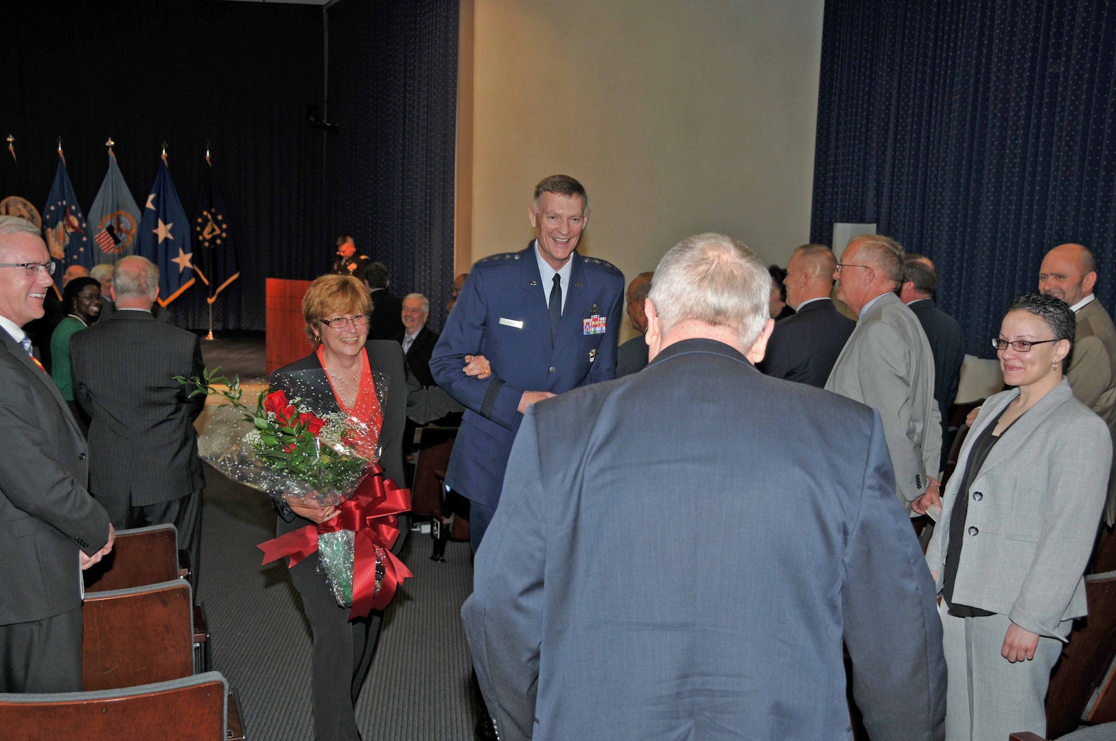 Ginger Pribble, who has been married to DLA General Counsel Fred Pribble for more than 30 years, is escorted from Pribble's retirement ceremony by DLA Director Air Force Lt. Gen. Andy Busch. Photo by Teodora Mocanu