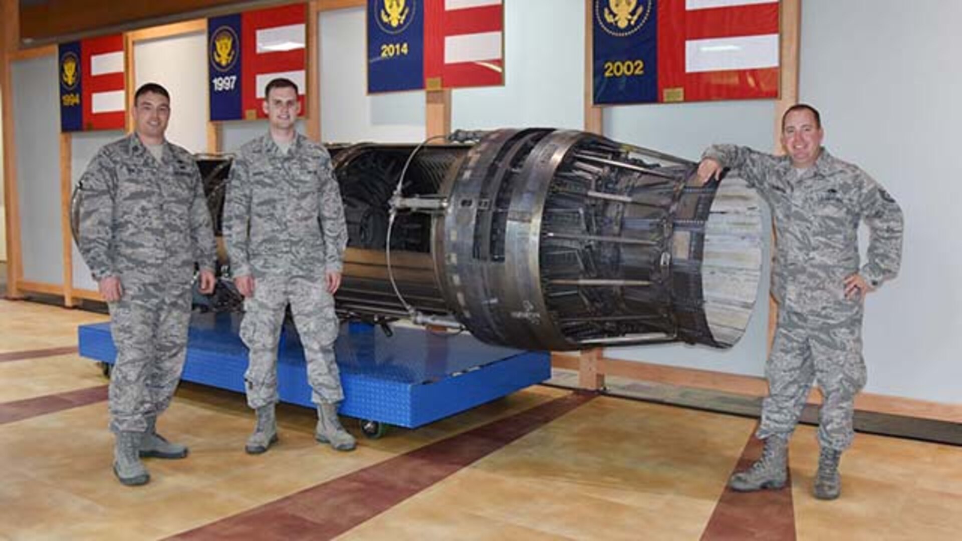 Air Force Capt. Robbie Walsh, left, Air Force Staff Sgt. Jeremy Garrett, center, and Air Force Tech Sgt. Brandon Gambrel, all from the Oklahoma City Air Logistics Complex, in Oklahoma City, pose next to the F-100 Engine Static Display they helped transport from Oklahoma to Defense Supply Center Richmond, Virginia.  The installation’s newest static display, which arrived on May 4, 2016, can be seen in the Frank B. Lotts Conference Center on DSCR. 