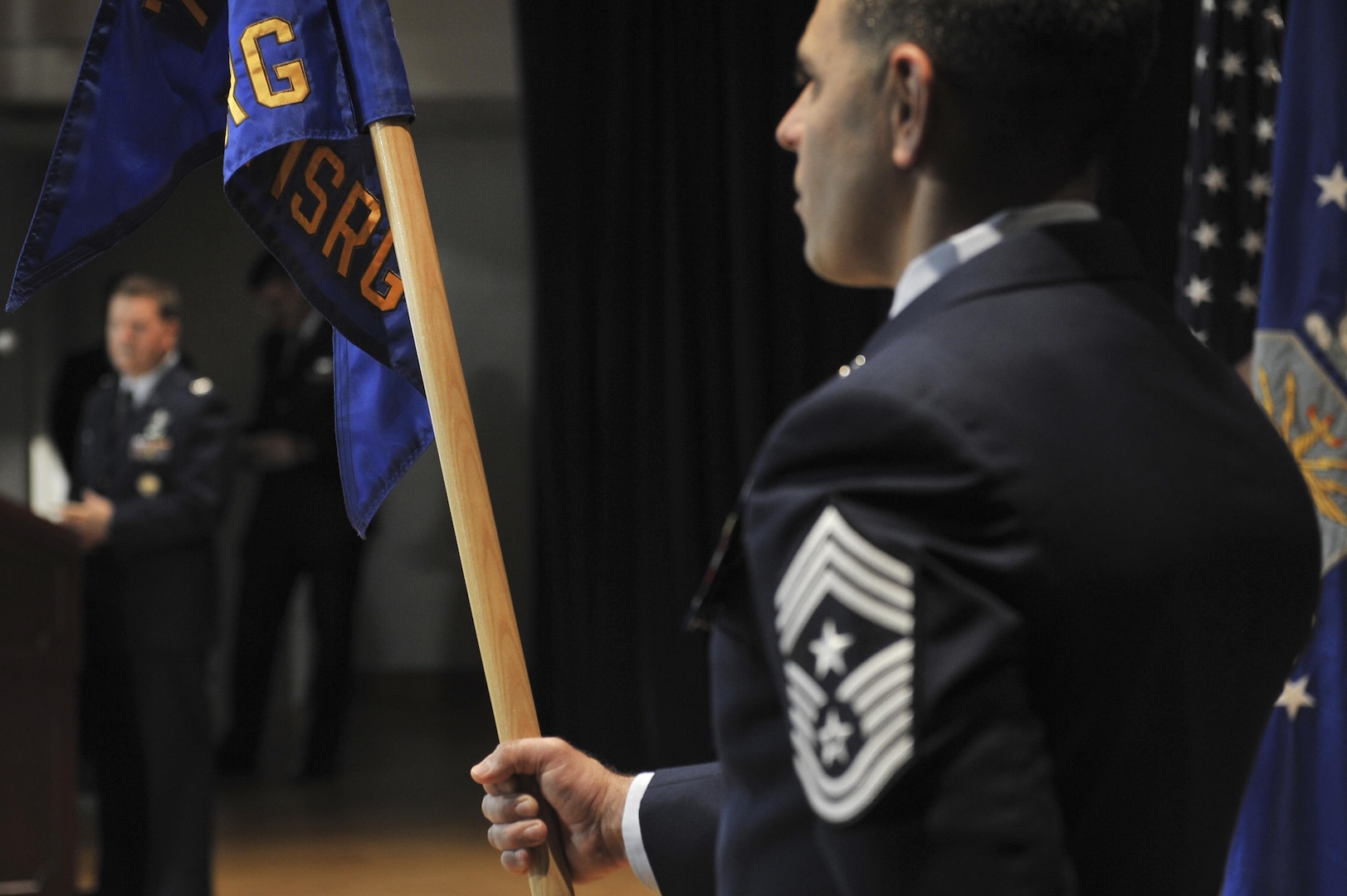 Chief Master Sgt. Benjamin Higginbotham, 70th Intelligence, Surveillance and Reconnaissance Wing command chief, holds the 691st  Intelligence, Surveillance and Reconnaissance Group flag as the new 691st ISRG commander,  Colonel David James, gives his final remarks during the 691st ISRG re-activation ceremony May 5, 2016, at Fort George G. Meade, Md. Officially in-activated September 2014 at Royal Air Force Menwith Hill Station, United Kingdom, the 691st ISRG returns and is now activated under the 70th ISR Wing. (U.S. Air Force photo/Staff Sgt. Alexandre Montes)